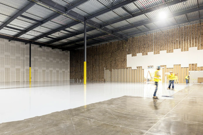Two construction workers in a large empty warehouse